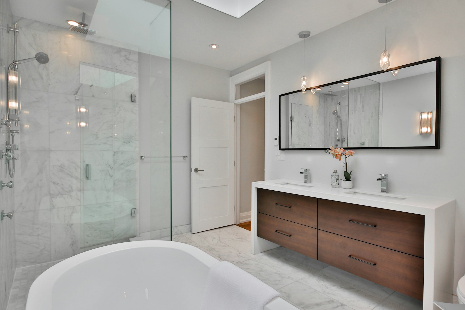 Mermer kaplı duvarları, çift lavabolu ahşap dolabı ve küveti olan modern banyo